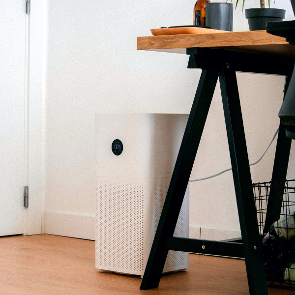 An image of an air purifier sitting next to a desk.