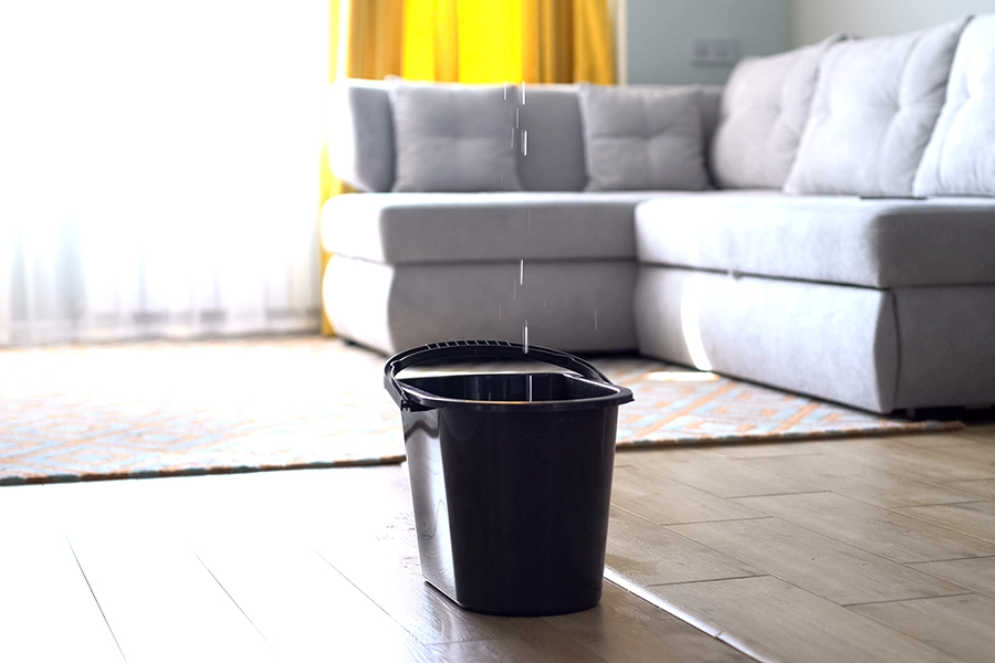 A bucket placed under a leaking roof to catch water, preventing further damage