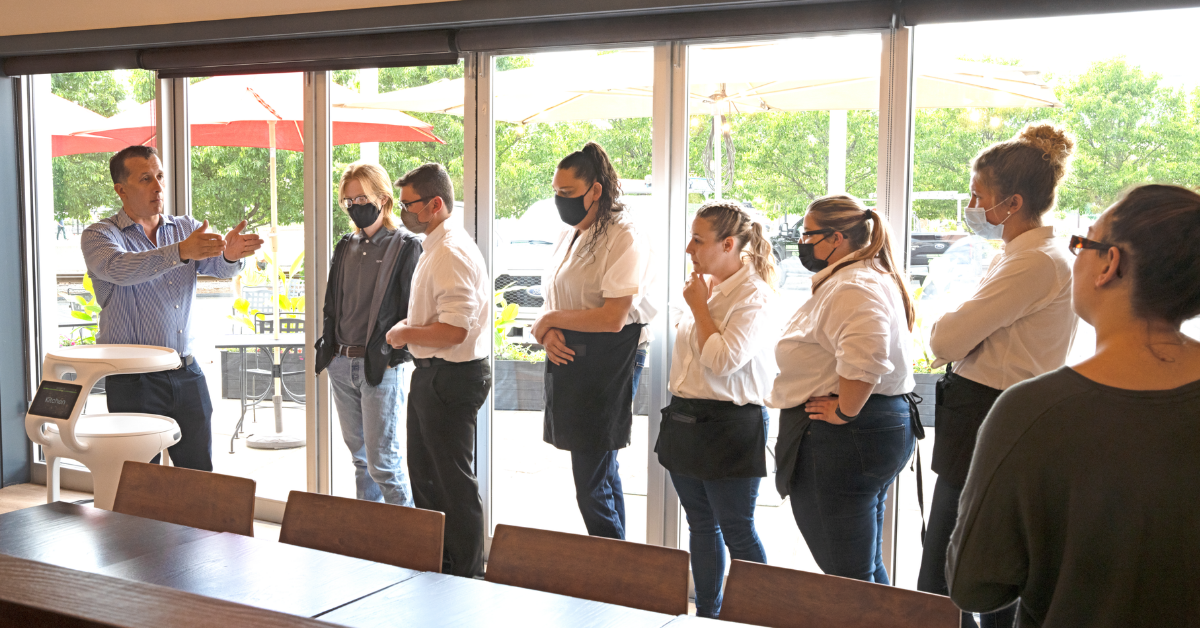 Workers learning how to use Servi robots and artificial intelligence serving hospitals from Bear Robotics.