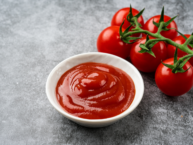 An image of ketchup next to tomatoes.