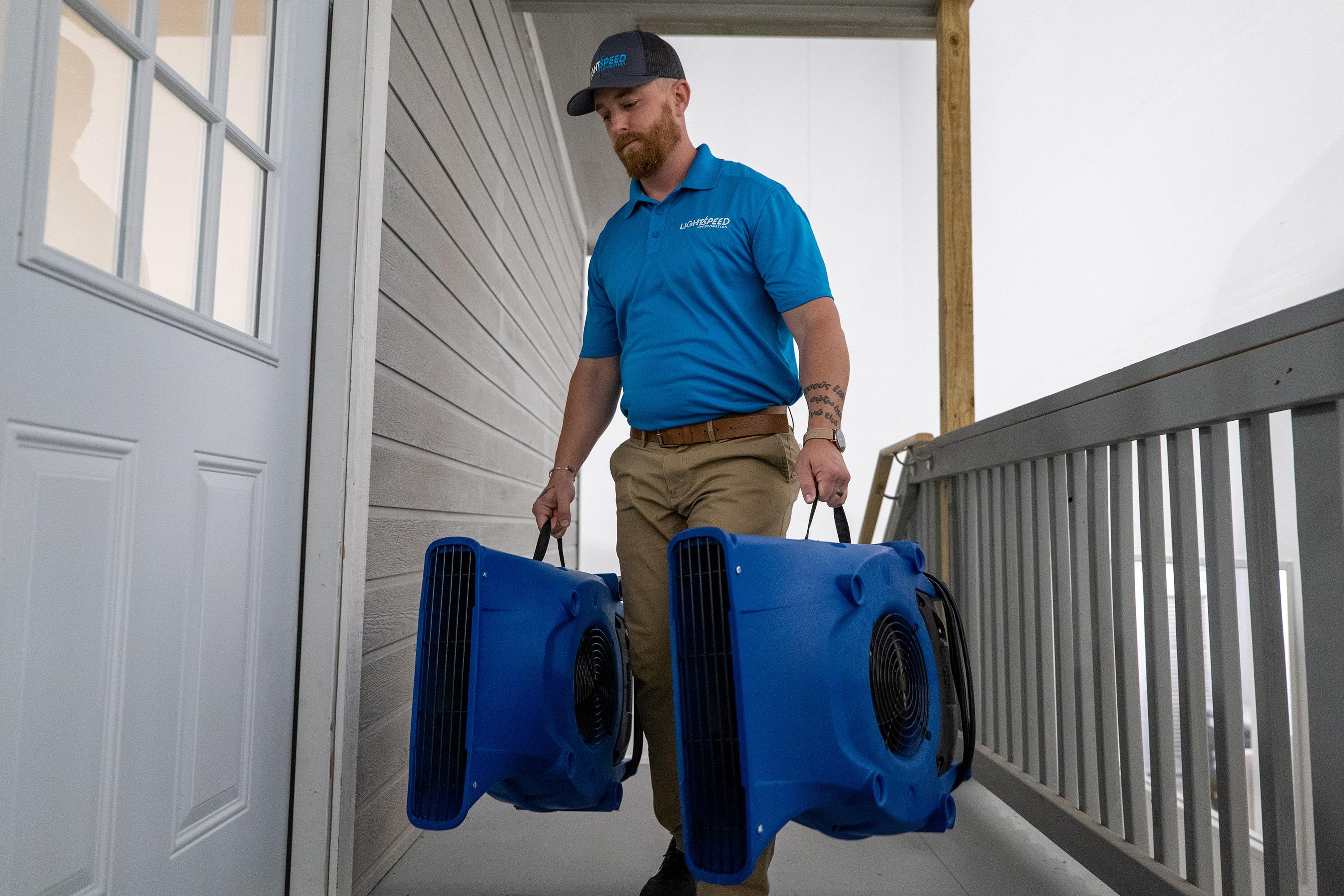 A technician is seen carrying specialized water extraction equipment into a home to address a plumbing leak, part of the water damage restoration process. This prompt action is crucial for preventing mold growth and minimizing further damage from the affected areas.