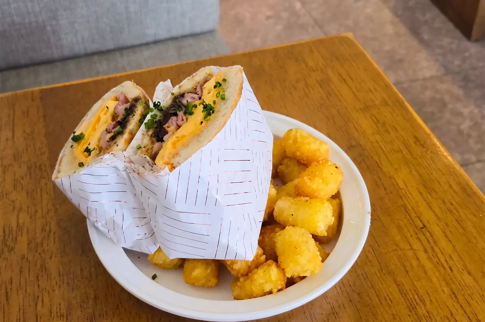 a serving of Breakfast Sammie with cheddar and chives scramble, aioli, back bacon, and caramelised onions.
