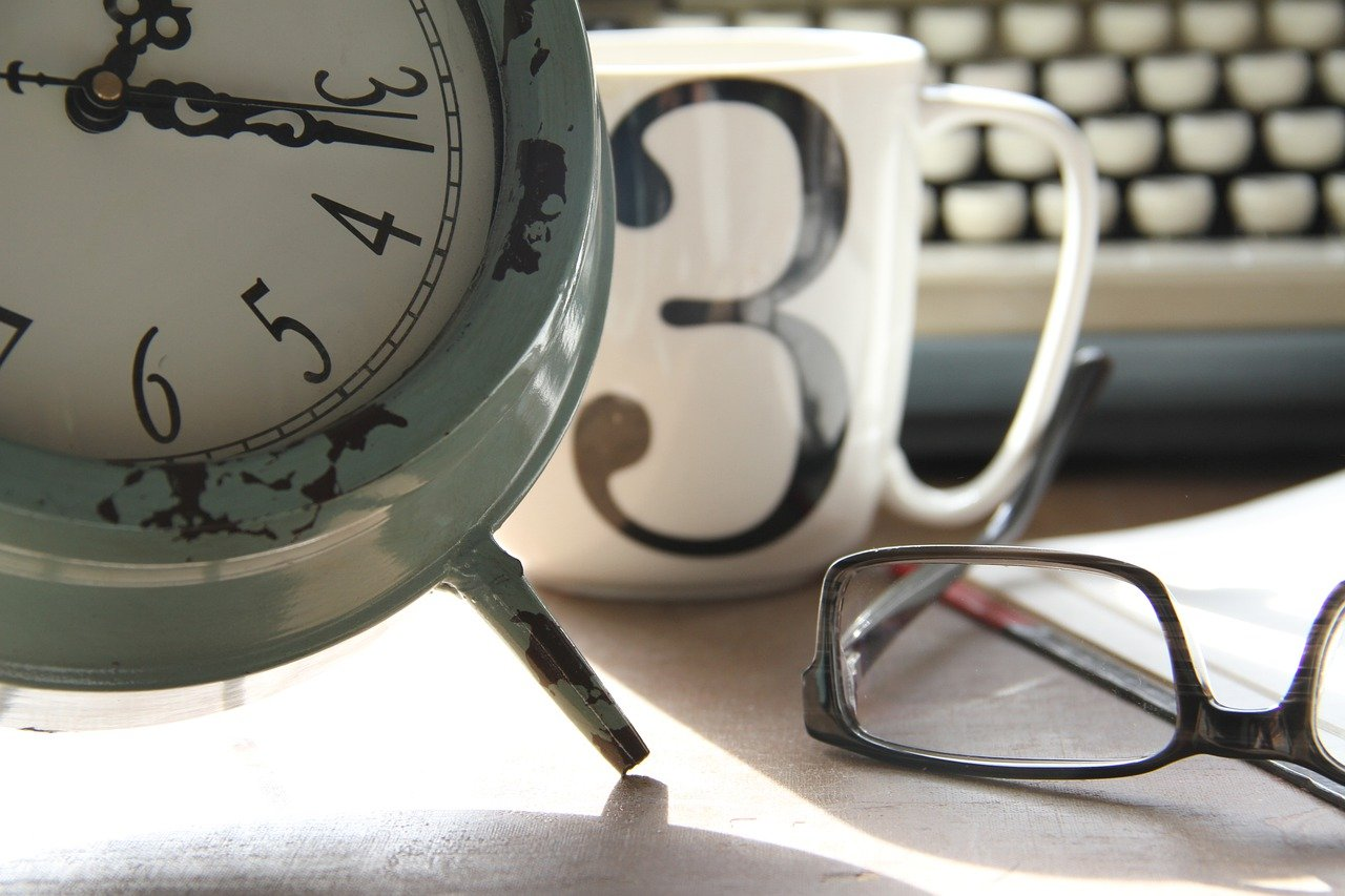 clock in an office with a white mug and glasses
