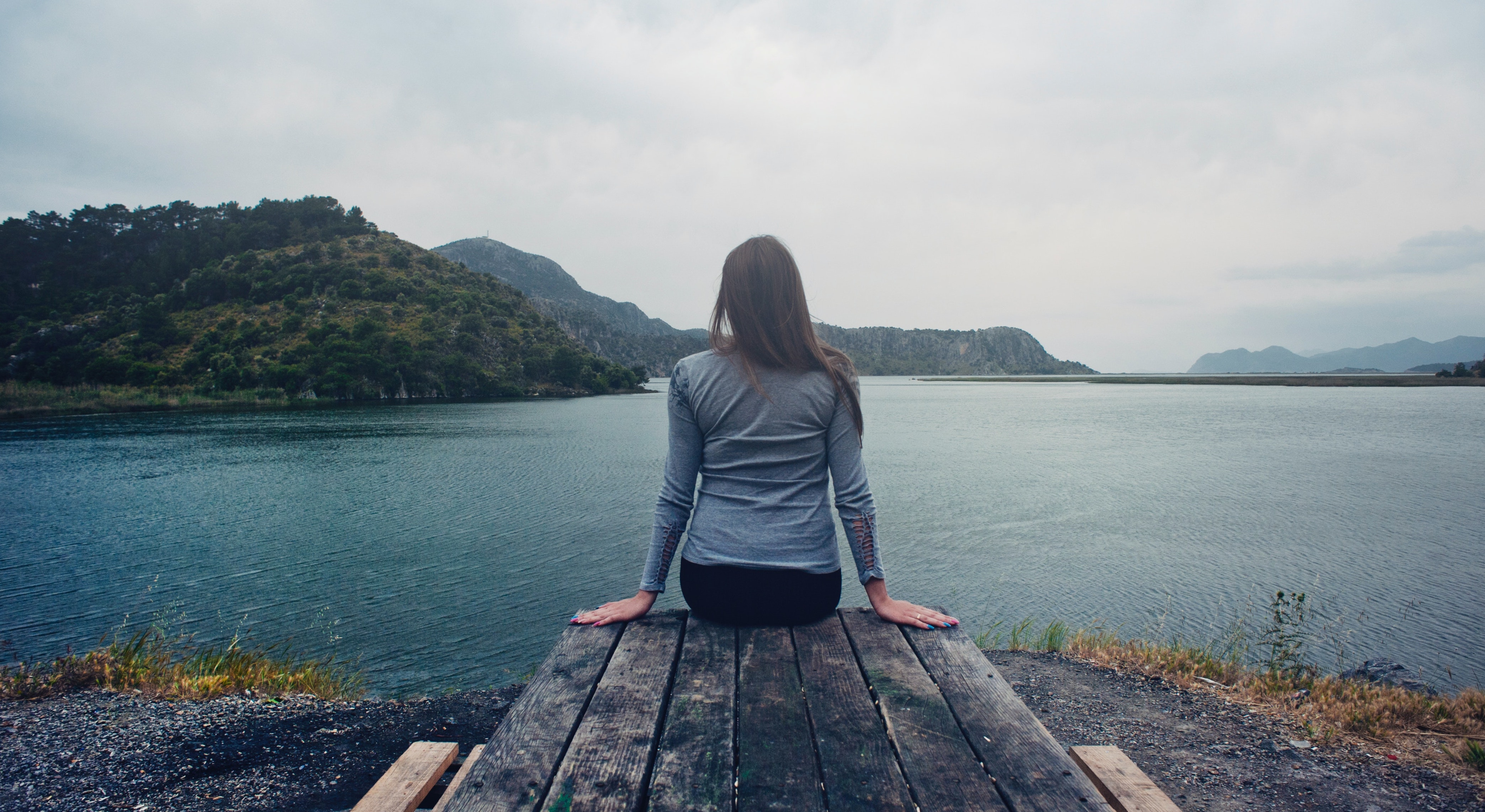 a woman sits on a dock to represent the side effects of hydrocodone. 