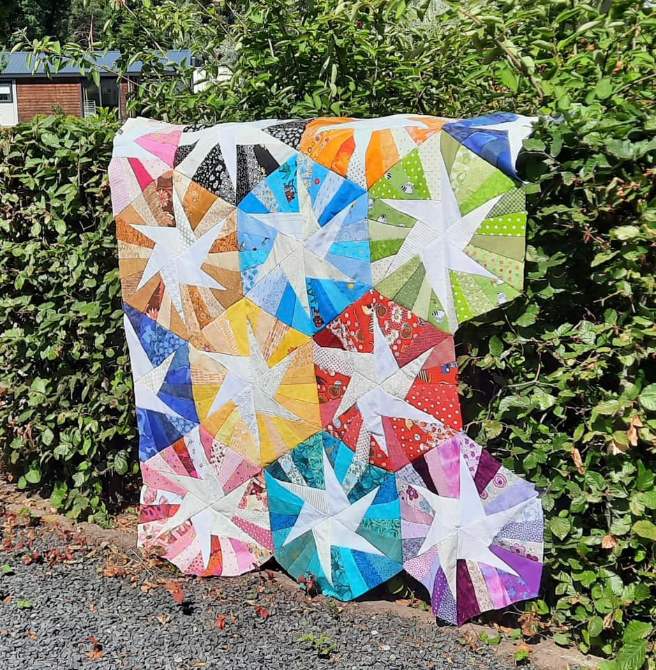 Image shows Janine's Scrappy Whirligig quilt made from one of our free quilt patterns