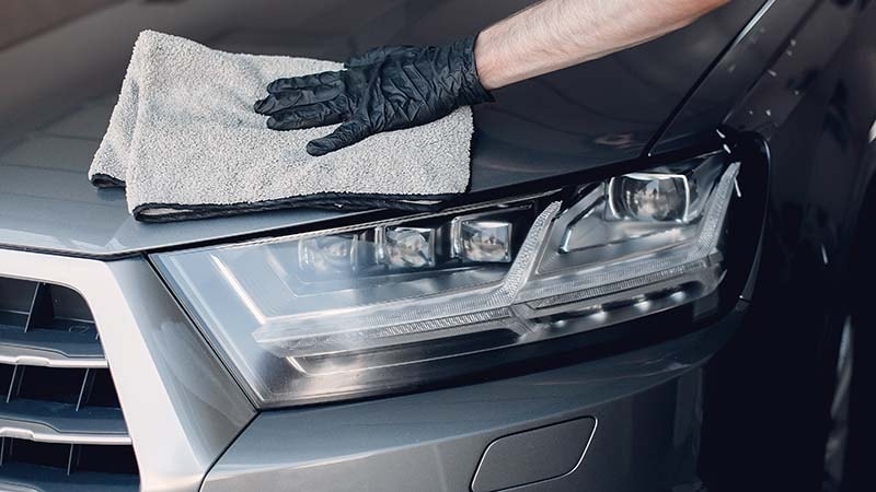 A man drying his car with a towel
