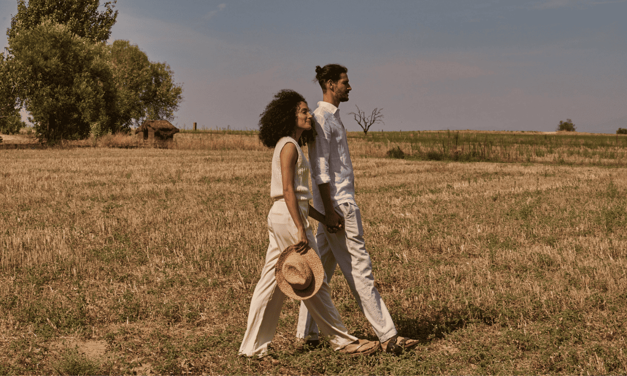 Couple walking in an open area holding hands.