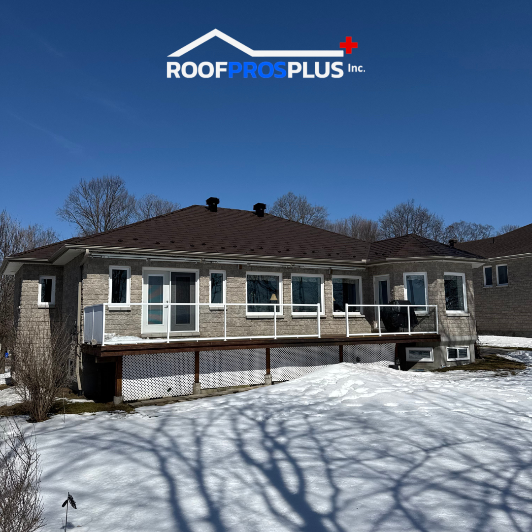 Image of a residential house with a metal roof and brick siding, surrounded by snow.