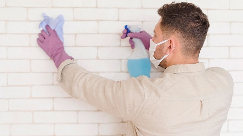 man cleaning painted brick wall