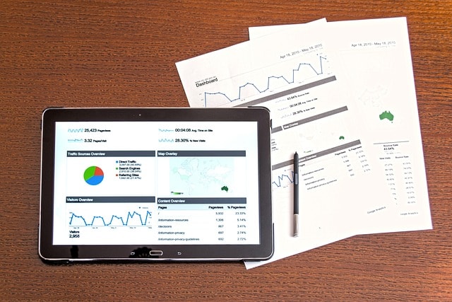 Tablet with two papers and a pen on a brown table