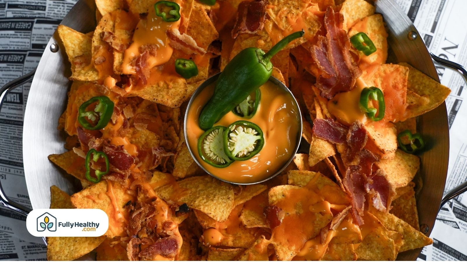 Nachos topped with cheese sauce bacon and fresh jalapeño slices