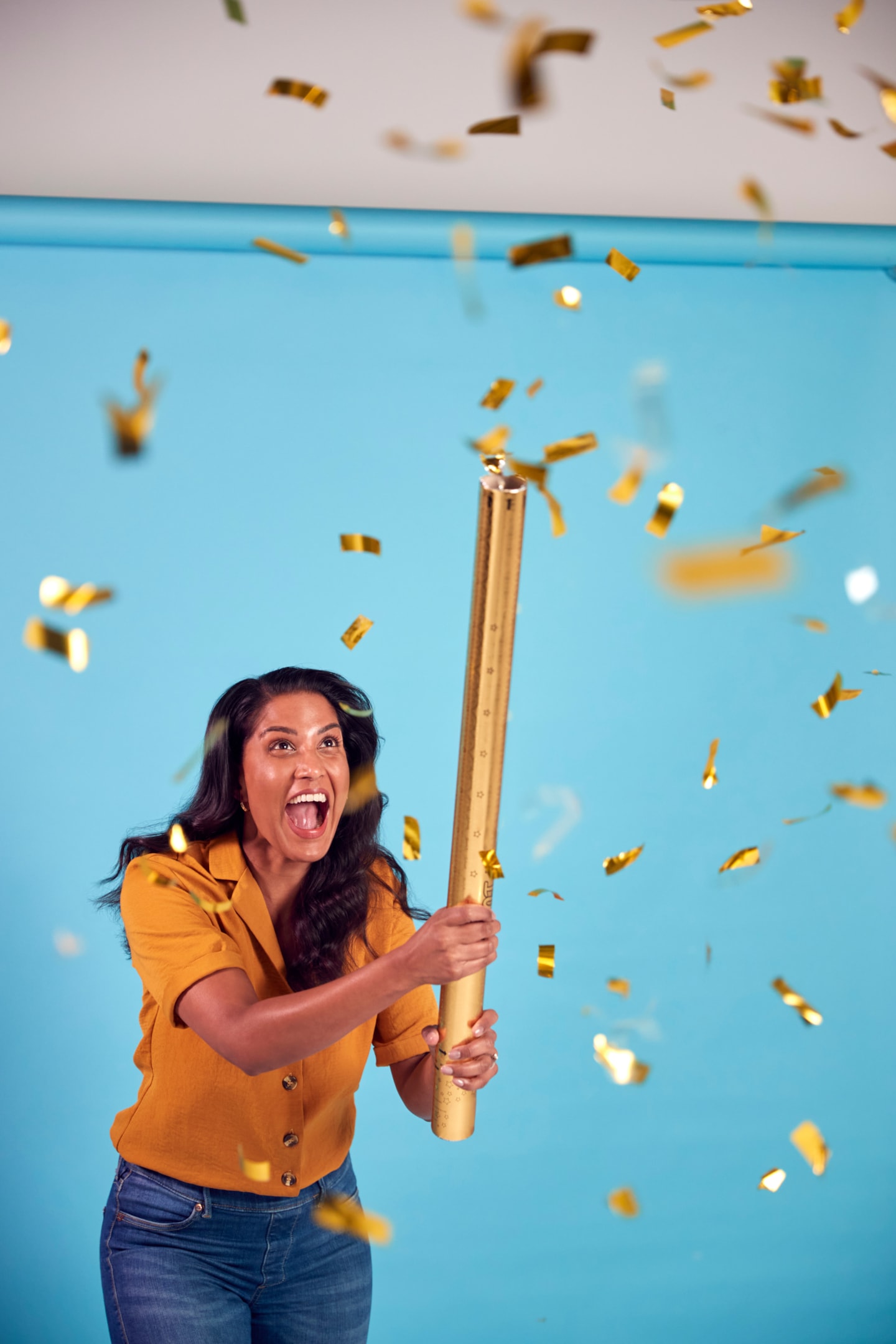 woman popping a gold confetti canon