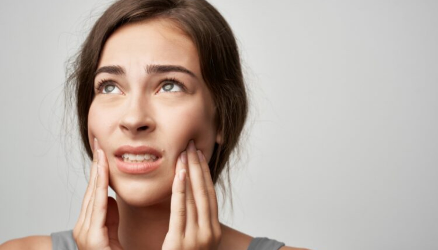 Tannpressing Symptomer: Når Du Ikke Vet At Du Gjør Det 15 Ung kvinne holder seg til kinnet med smertefullt uttrykk, mulig tegn på tannverk eller kjevesmerter.
