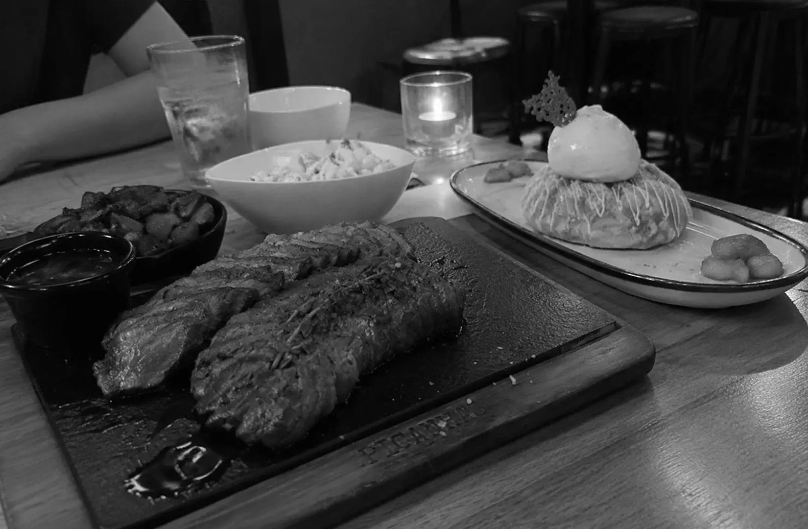 Grilled steak served with sides and a plated dessert in a casual dining restaurant.