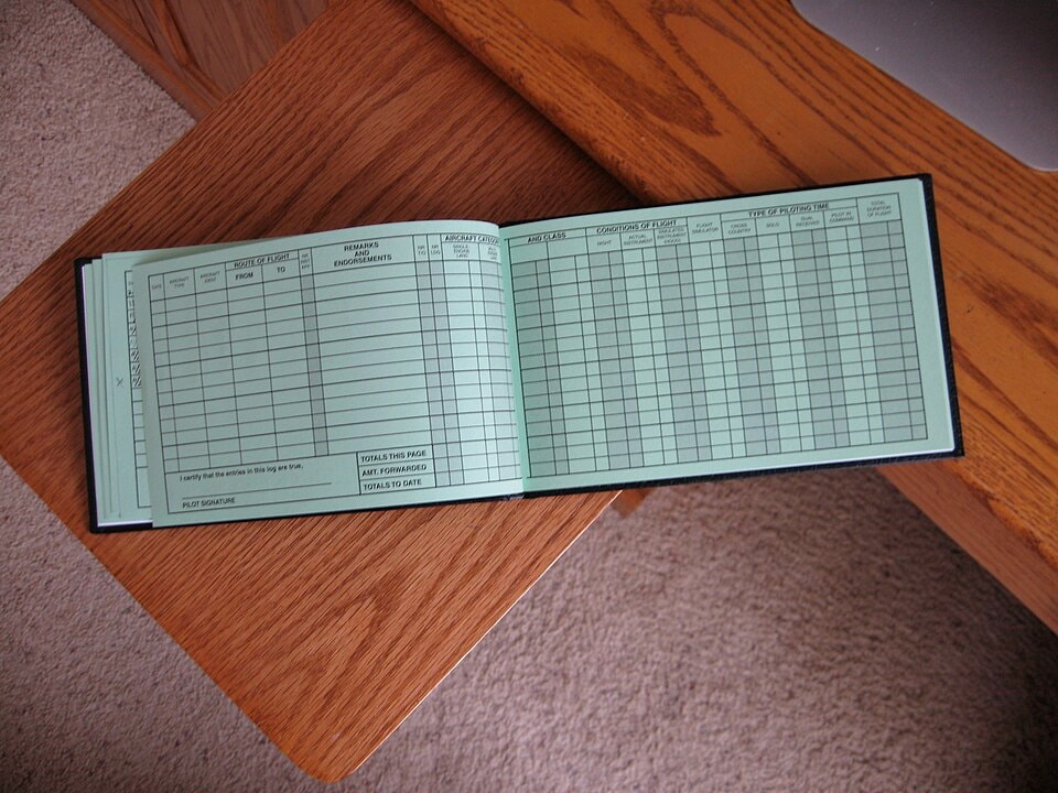 A pilot logging flight hours in a logbook, emphasizing best practices.