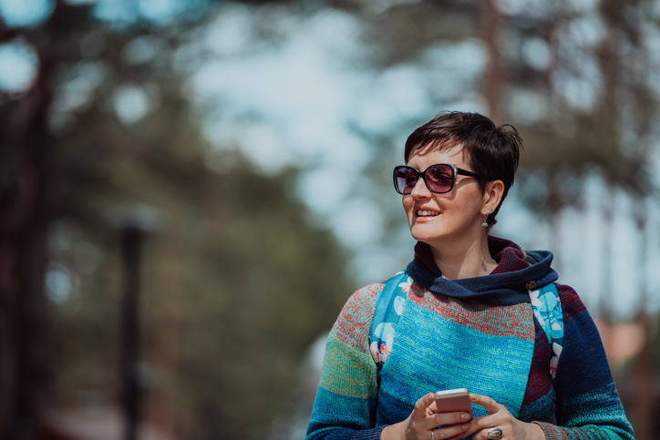 Woman with short dark hair and sunglasses out for a walk.