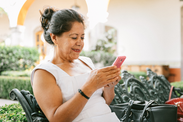 Older woman in a white shirt sending a text.