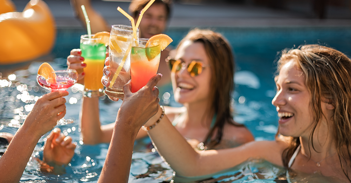 Friends celebrating with colorful drinks in a private pool at a Point Pleasant Beach vacation rental — find house rentals with private pools on ShoreSummerRentals.com