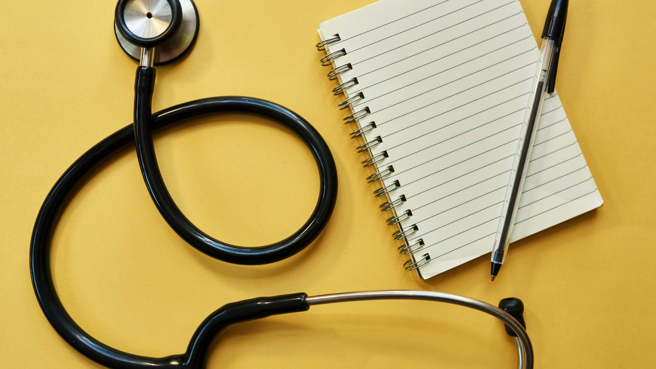 An image of a stethoscope and a blank writing pad.