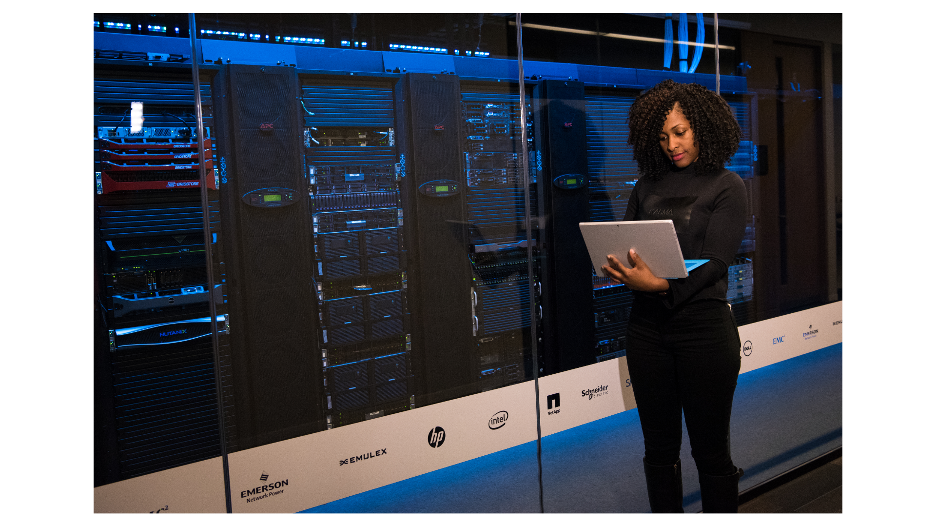 A person works on a laptop in a server room.
