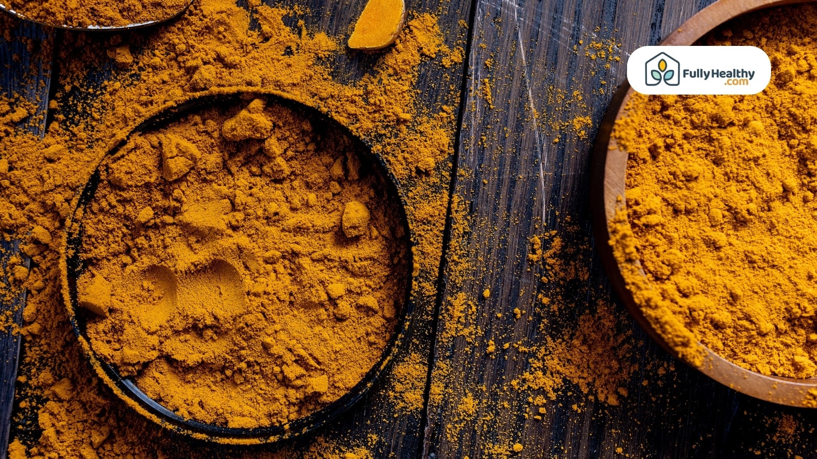 Turmeric powder scattered across wooden surface with filled containers nearby