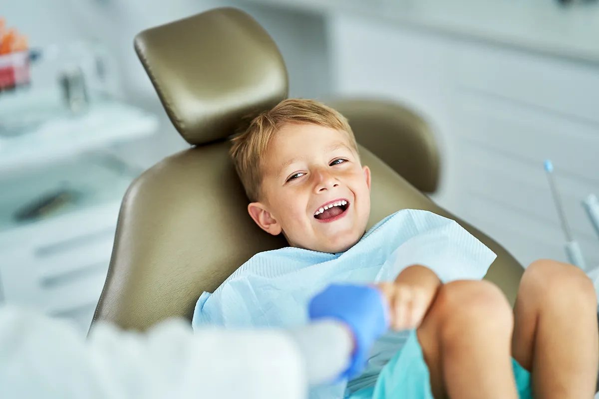 Smiling boy in dental chair enjoying pediatric dental appointment.