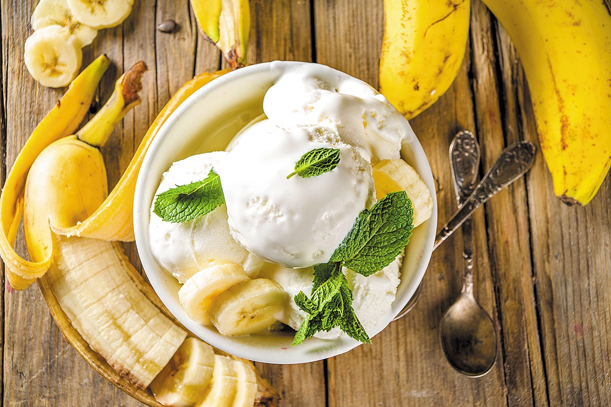 Na imagem: um pote de sorvete com bananas ao redor.