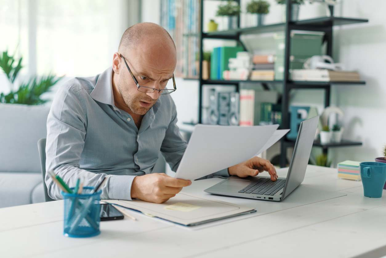 An image of a person holding a resume and looking at job listings online, representing the challenge of reinventing your career after 50 navigating job loss with grace during retirement planning.