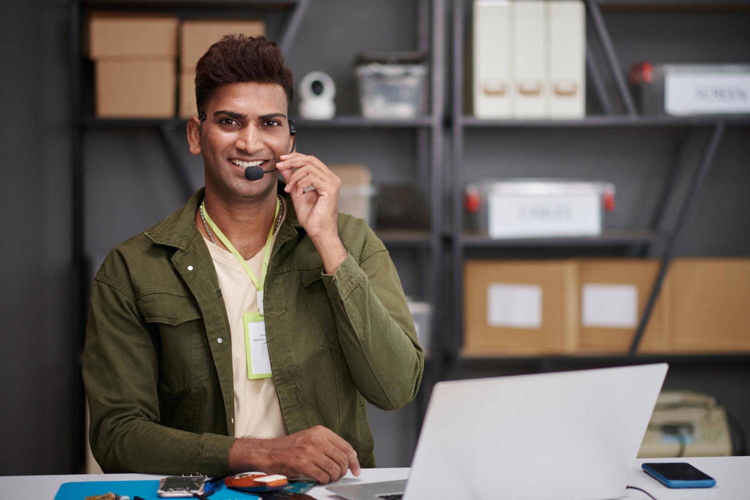 Technical support specialist smiles while using a simple business phone system headset, enabling efficient and affordable business communication in a tech workspace.