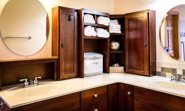 An image of a bathroom sink with mirrors, cabinets, and towels in cubbies. 
