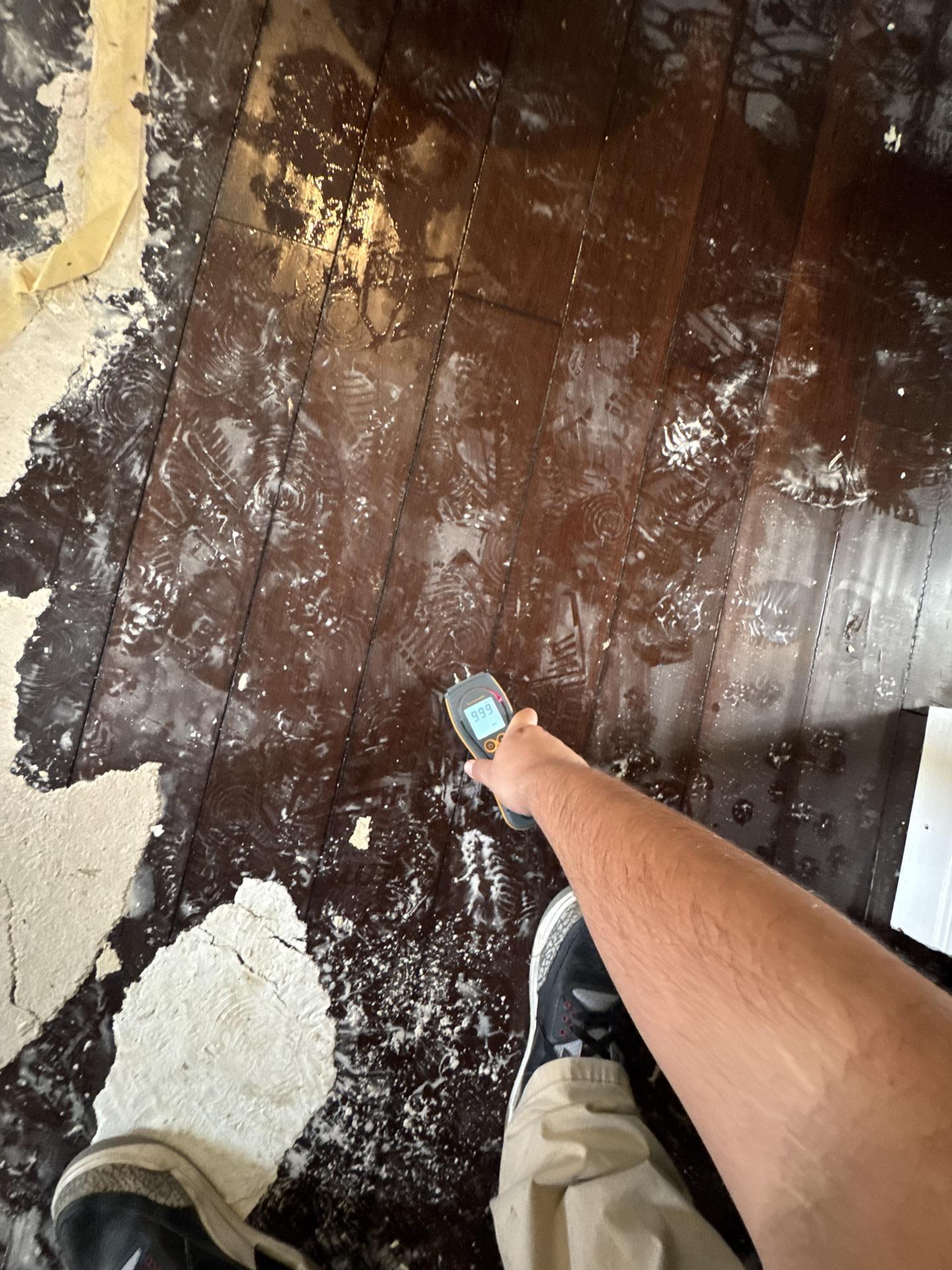 A restoration technician is inspecting a floor for moisture levels following water damage, using advanced equipment to assess potential mold growth and hidden moisture. This crucial step in the flood damage restoration process helps prevent further structural damage and ensures effective water damage restoration services.