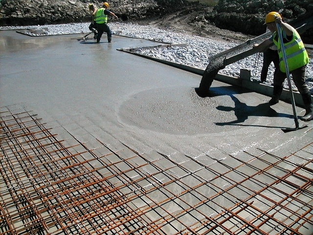 A picture of a construction site with workers pouring self consolidating concrete into formwork
