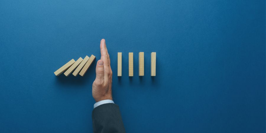 Hand stopping more dominoes from falling