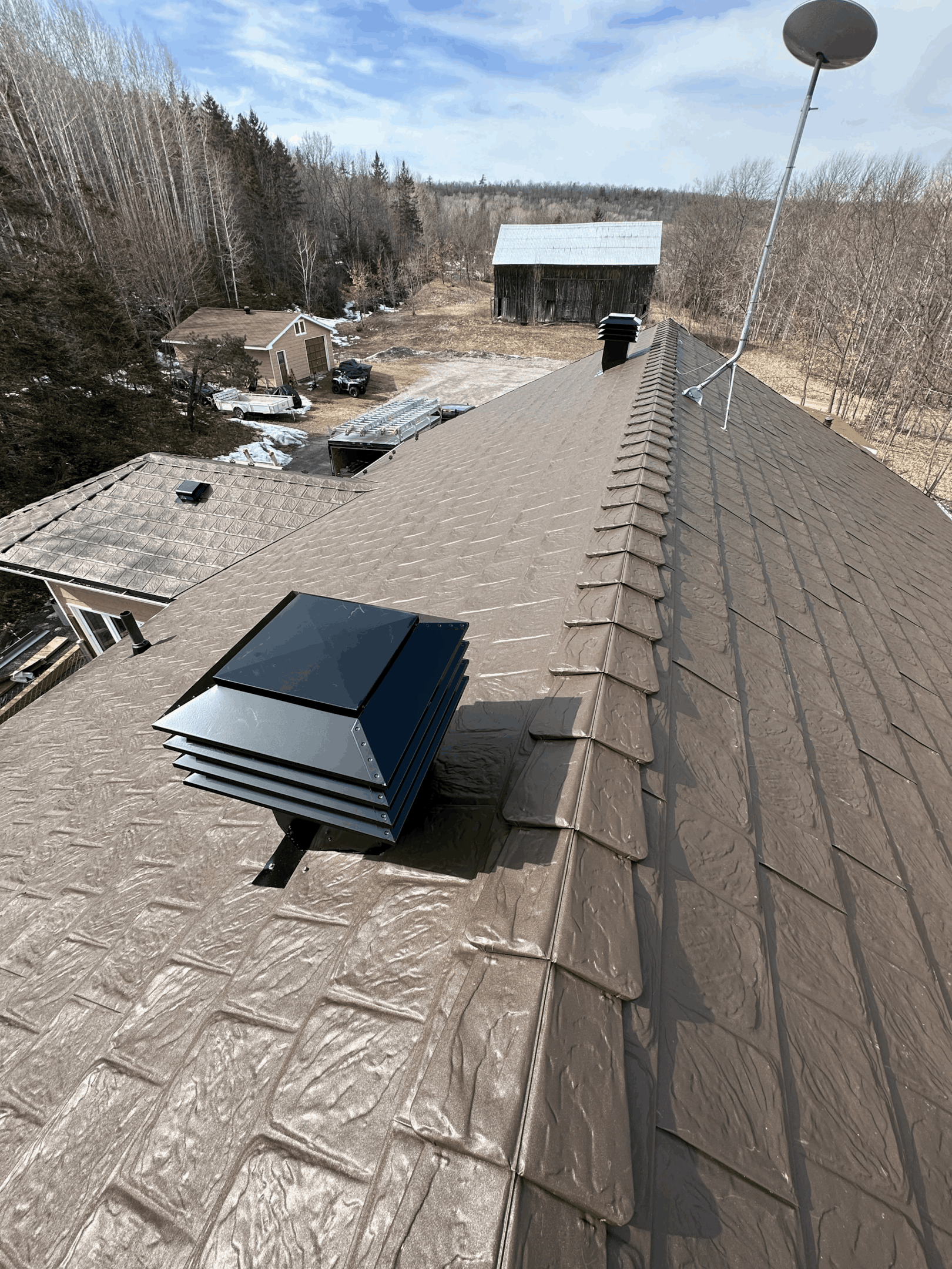 A close-up view of a brown metal roof with a distinct black vent integrated into its structure.