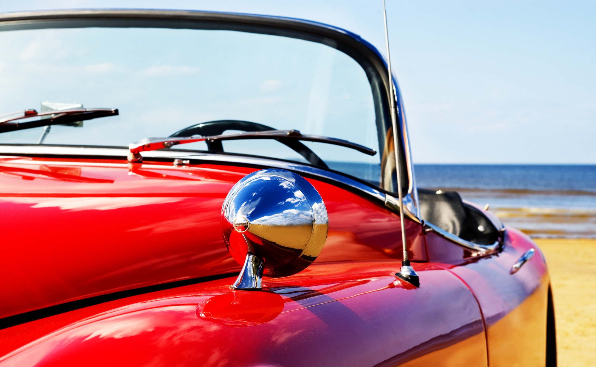 Old cabriolet with curved laminated glass on the beach