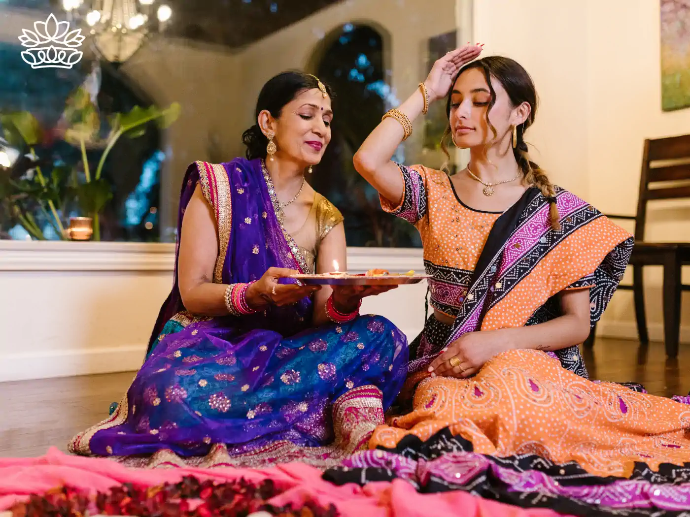 Mother and daughter in vibrant sarees performing traditional rituals during Diwali, sharing a moment of cultural heritage and familial bonding. Diwali. Delivered with Heart by Fabulous Flowers and Gifts.