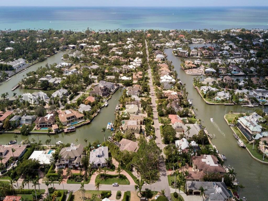 An aerial view of Aqualane Shores showcases its intricate canal system lined with luxurious homes, highlighting the desirable waterfront living in Naples, Florida. The image captures the stunning architecture and sprawling outdoor spaces of these prestigious residences, emphasizing the beauty of this quaint waterfront neighborhood.