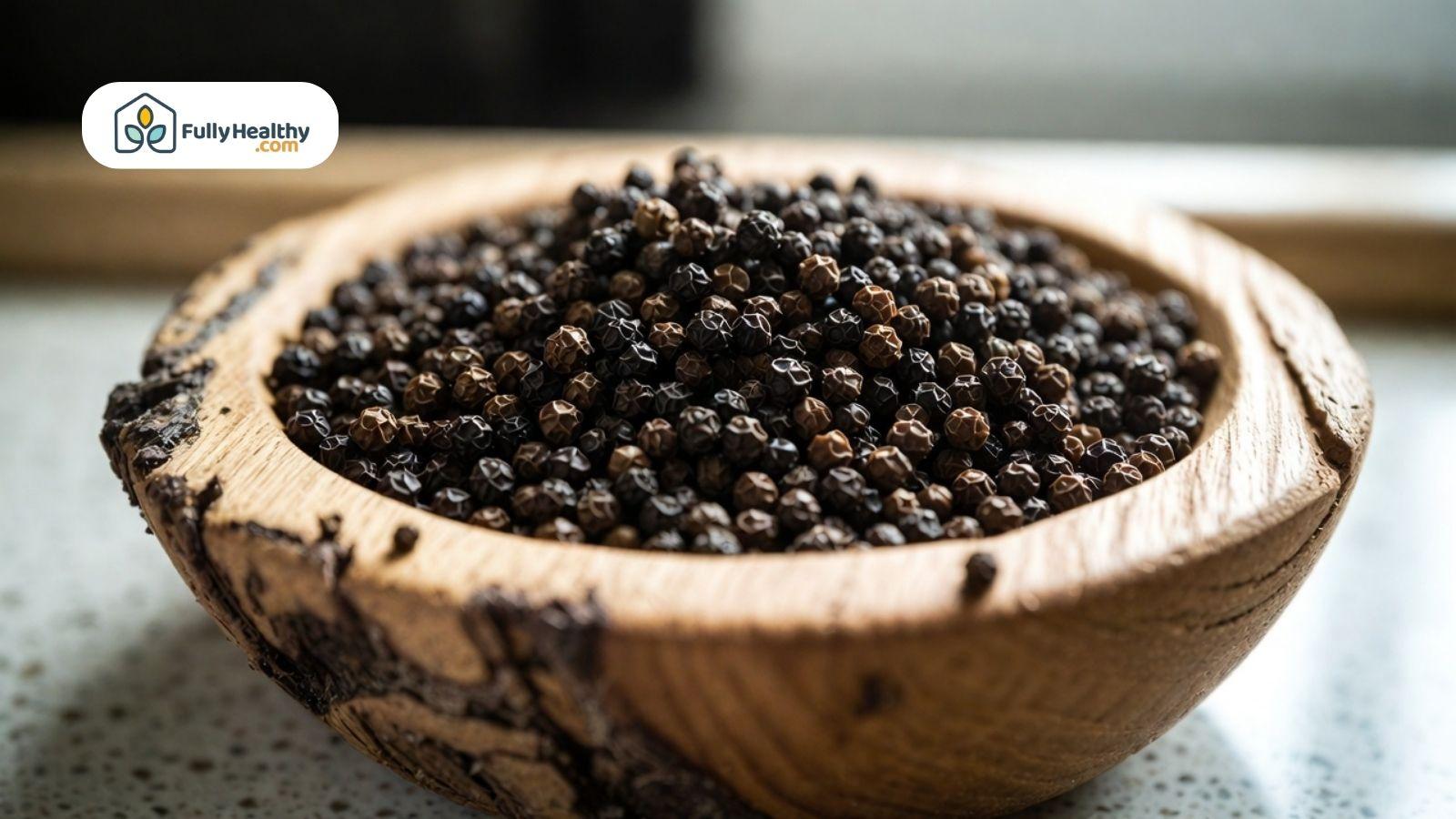 Bowl of whole black peppercorns in a wooden dish.