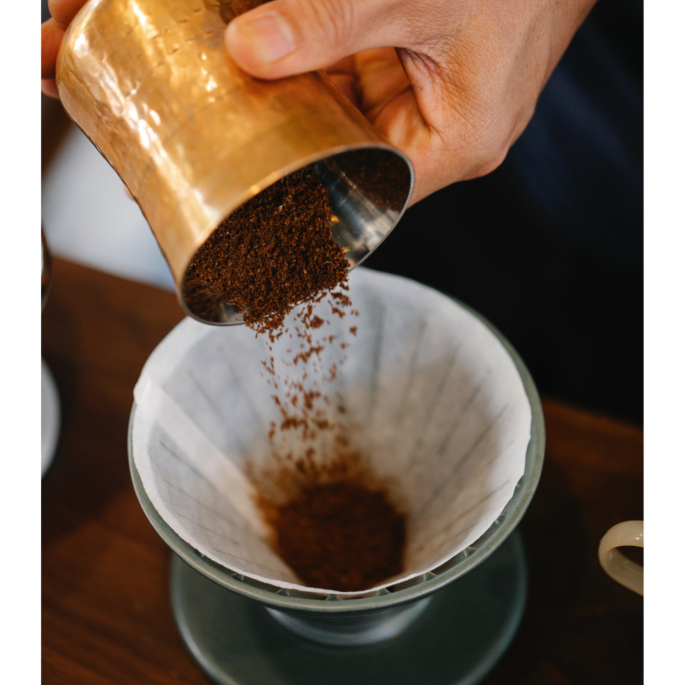 A close-up image of freshly roasted best coffee for pour over coffee maker beans being poured into a coffee grinder.