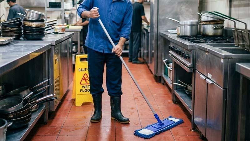 A man is cleaning the kitchen floor with a pocket mop