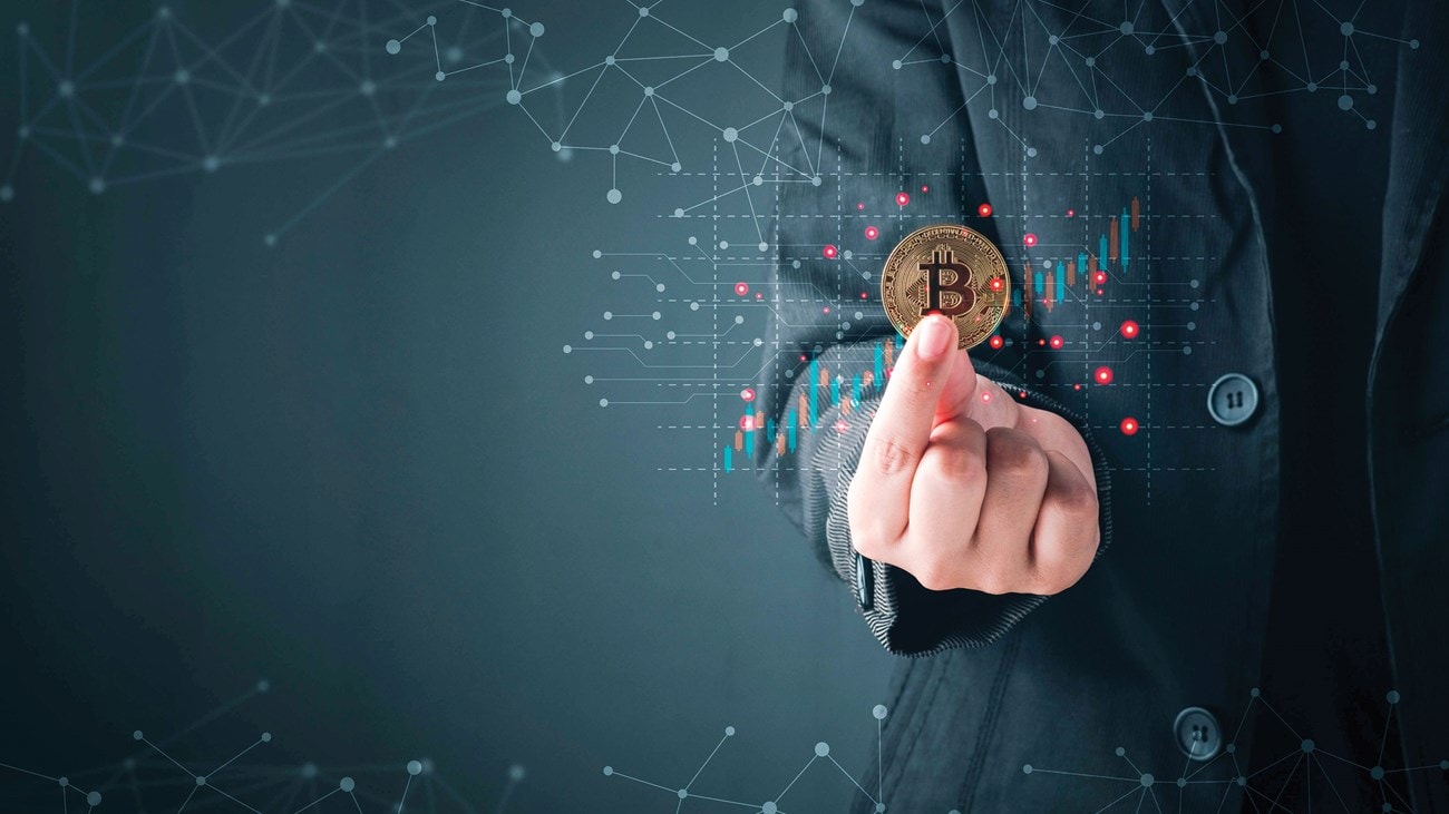 شخص ببدلة رسمية يحمل عملة بيتكوين، مع خلفية رقمية تحتوي على مخططات وأسلاك متصلة