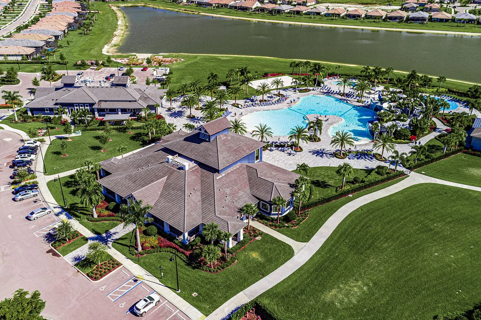 The image depicts a beautiful gated entrance to The Place at Corkscrew community, featuring lush landscaping that enhances its resort-style ambiance. This master-planned community in Estero, Florida, offers residents a lifestyle filled with amenities such as a fitness center, pool, and restaurant, making it an attractive location for families and buyers alike.