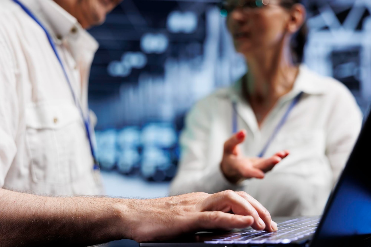 A blurred background shows two professionals engaged in conversation while one types on a laptop. The image represents managed telecom services, VoIP, and call routing.