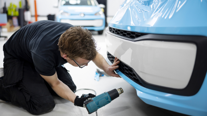 A mechanic is using Heat Gun to apply PPF correctly