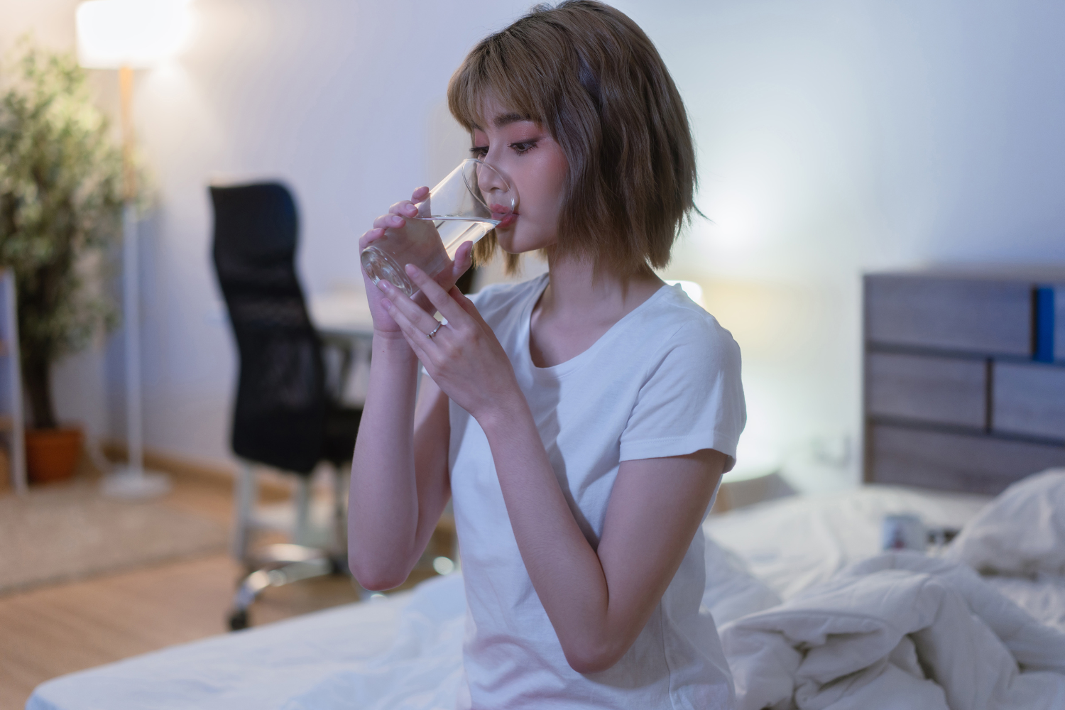Woman drinking a glass of electrolyte water before bed.