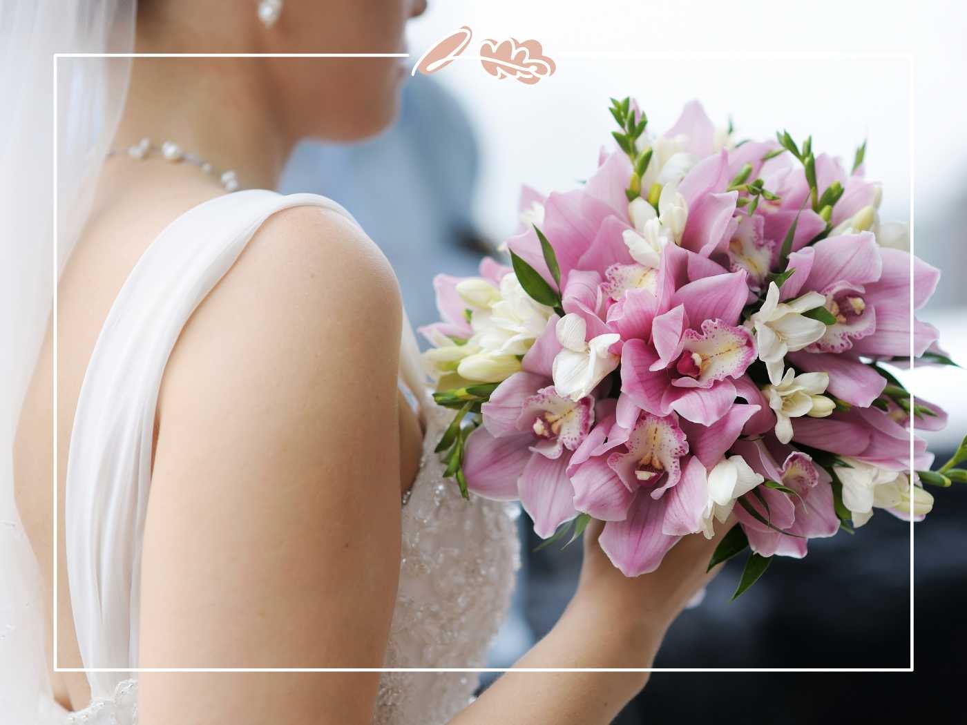 A bride holding a delicate bouquet of pink and white flowers, captured in a moment of wedding bliss. Fabulous Flowers and Gifts.