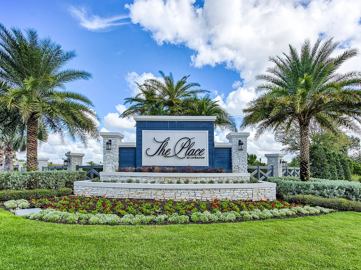 The image depicts a vibrant scene of people enjoying tennis on well-maintained courts surrounded by lush palm trees, with a clubhouse visible in the background. This setting exemplifies the resort-style amenities offered in the master-planned community of the Place at Corkscrew in Estero, Florida.