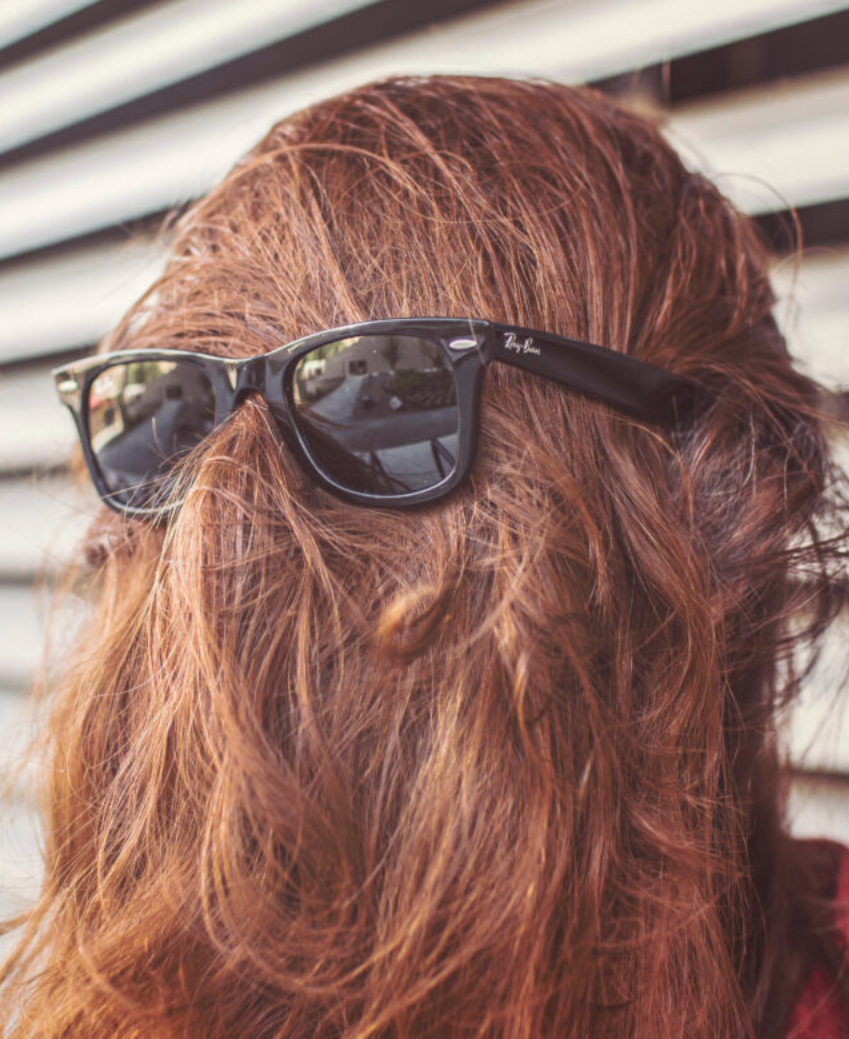 Man with hair over his face and Rayban sunglasses