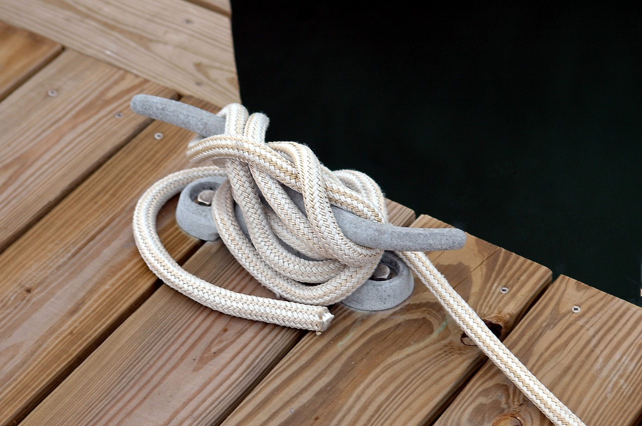 White Polyester rope used as a mooring line in a dock with wooden floorboards on the background