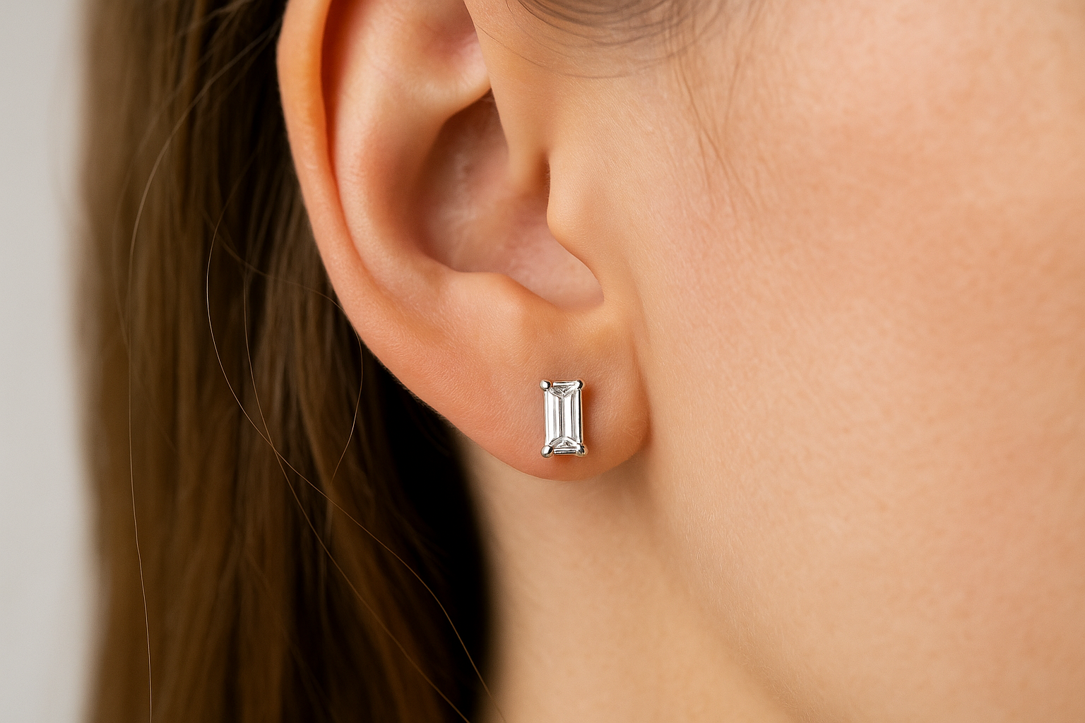 Auskarai su baguette formos deimantais baltame aukse ant moters ausies.